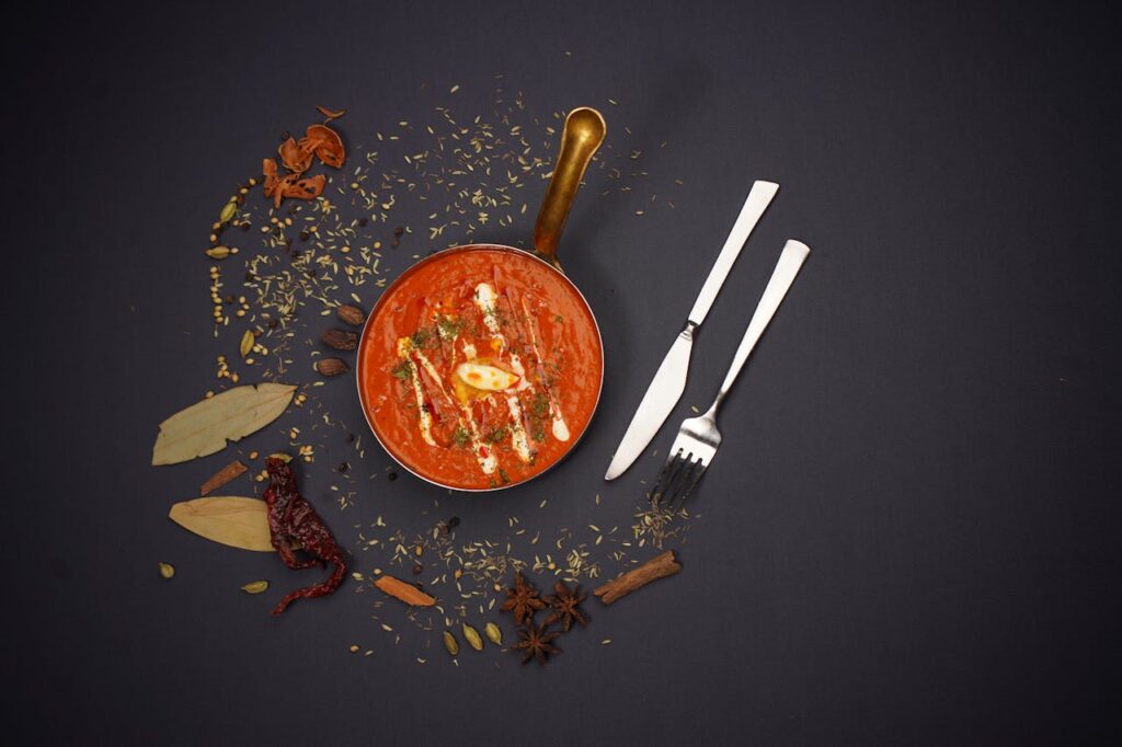High-end food photography of Indian tomato soup with spices, shot in a studio.