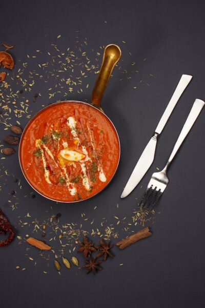 High-end food photography of Indian tomato soup with spices, shot in a studio.