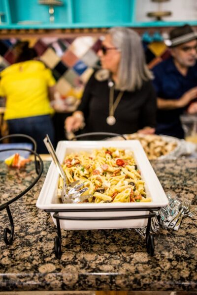 Appetizing pasta dish at a buffet with chefs preparing in the background